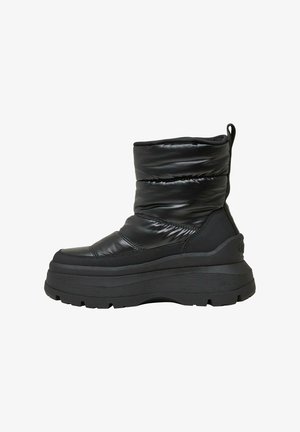Schwarze gepolsterte Ankle Boots mit einem eleganten Design, ausgestattet mit einer strukturierten Oberfläche, dicke Plattformsohle und einer hinteren Schlaufe für ein einfaches Anziehen.