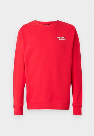 Red sweatshirt made of cotton. Features long sleeves, ribbed cuffs, crew neck, and a white "RED BULL RACING" logo on the chest.