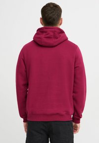 Sudadera burdeos con cordón ajustable, puños y dobladillo acanalados. Textura suave, corte relajado, diseño liso y sin logotipos o patrones visibles.