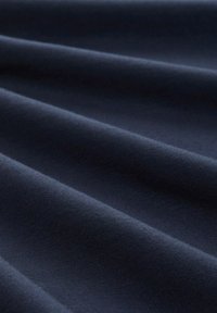 Dunkelmarineblauer Stoff mit glatter Textur, der subtile Wellen und Falten aufweist, was auf flexible Materialien hinweist. Die reiche, tiefe Farbe verstärkt die Tiefe.