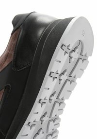 Baskets en cuir noir et suède marron avec une semelle en caoutchouc texturé présentant des motifs de grip multidirectionnels et un design de bout arrondi.