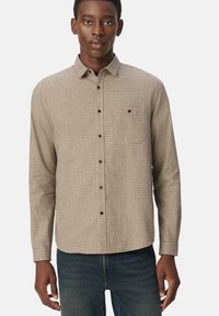 Bruin en crème geruite lange mouwen overhemd met een knoopsluiting kraag, voorzak en zwarte knopen, gecombineerd met donkerblauwe jeans.