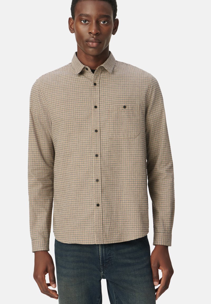 Bruin en crème geruite lange mouwen overhemd met een knoopsluiting kraag, voorzak en zwarte knopen, gecombineerd met donkerblauwe jeans.