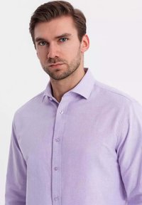 Camisa de botones de lavanda clara hecha de una tela suave, con un cuello puntiagudo y botones estándar en la parte delantera.