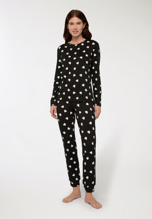 Set di loungewear nero composto da una maglietta a maniche lunghe e pantaloni coordinati con motivi a cuore bianchi. Tessuto morbido e elasticizzato con polsini aderenti.