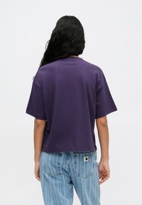 Violeta īsā blūze ar īsām piedurknēm un apaļu dekoltē, izgatavota no kokvilnas, apvienota ar augstā vidukļa gaiši zilām svītrainām zābakiem.