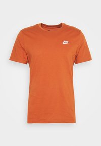 Oranžové bavlněné tričko s kulatým výstřihem, krátkými rukávy a bílým logem Nike na levé části hrudi. Hladká textura, běžný střih.