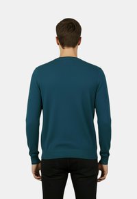 Maglione di cotone turchese con maniche lunghe, scollo rotondo e polsini e orlo a coste, con una texture liscia e una forma aderente.
