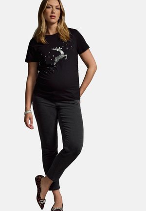 Sort t-shirt med sølvfarvet paliettsdyr grafik og stjerner. Sammen med mørkegrå slim jeans og dyreprint flade sko. Armbånd på håndleddet.