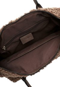 Brun fløjl tote bag indvendig, der har en lynlåslomme, glat tekstilforing og et lille mærke fastgjort indeni.