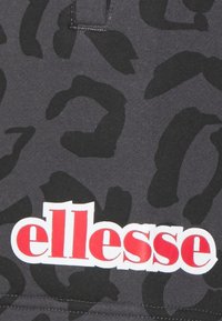 Černá látka s leopardím potiskem. Název značky "ellesse" je zobrazen tučně červenými a bílými písmeny na spodní části.
