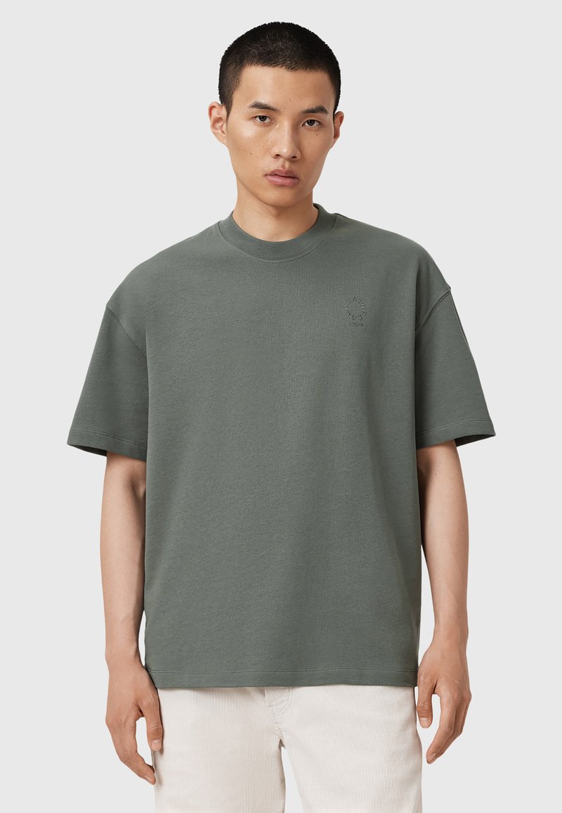 Oliven grøn bomulds t-shirt med afslappet fit, korte ærmer, ribbet rund hals og lille broderet detalje på brystet.