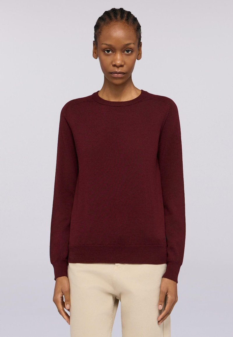 Maglione bordeaux a collo giro con maniche lunghe, texture a maglia e polsini e orlo a coste. Abbinato a pantaloni beige chiari per creare un contrasto.