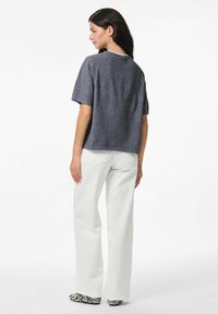 Pelēks īsu piedurknju tops ar kvadrātveida siluetu, ar apaļu kakla izgriezumu. Kombinēts ar baltām platām biksēm un melnbaltiem apaviem ar rakstu.