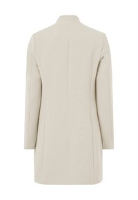 Abrigo beige a medida con cuello alto, mangas largas y una silueta estilizada. Textura suave, ideal para combinar en capas.