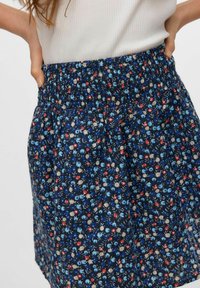 Falda floral azul marino con cinturilla elástica, presenta un estampado de flores de pequeño tamaño en azul, rojo y beige sobre una tela texturizada.