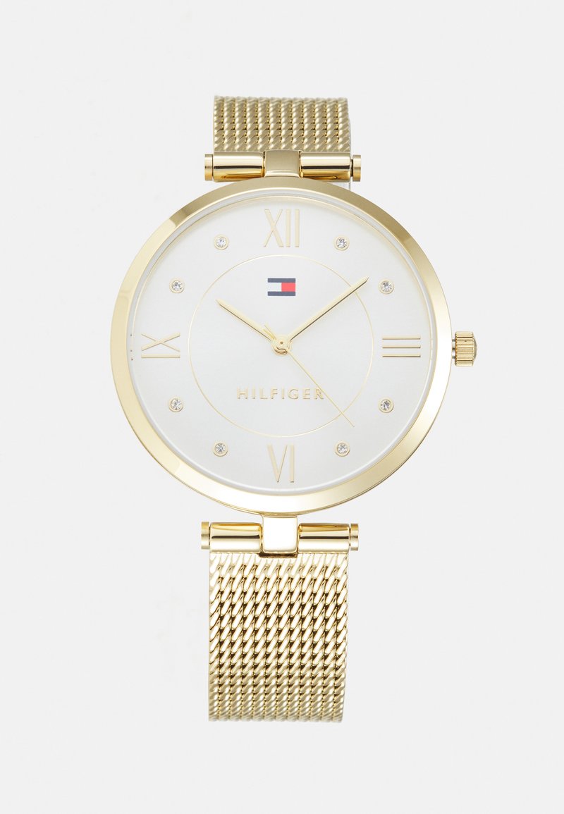 Orologio con cinturino a rete dorata, quadrante rotondo, fondo bianco, numeri romani, piccole gemme come indicatori e dettaglio del logo in rosso e blu.