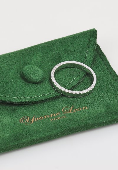 Inel argintiu cu mai multe pietre mici, clare, montate într-un rând. Așezat pe o punguță din suede verde cu litere aurii, "Yvonne Leon, Paris."