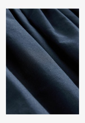 Tela azul marino con una textura suave, que presenta pliegues verticales que crean una sutil profundidad y dimensión.