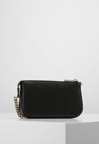 Bolso bandolera de cuero negro con un acabado texturizado, correa de cadena en tono dorado y cierre de cremallera, que presenta una forma redondeada y un diseño minimalista.