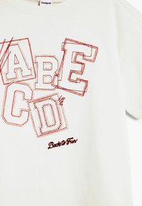 Bijela pamučna majica s velikim crvenim izvezenim slovima "A," "B," "C," "D," i natpisom "Back to Fun" u kurzivu na dnu.
