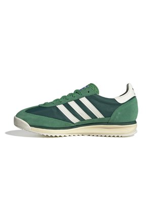 Groene en donkergroene Adidas sneaker met witte strepen, witte hieltab en beige zool, getoond vanaf de buitenkant op een witte achtergrond.