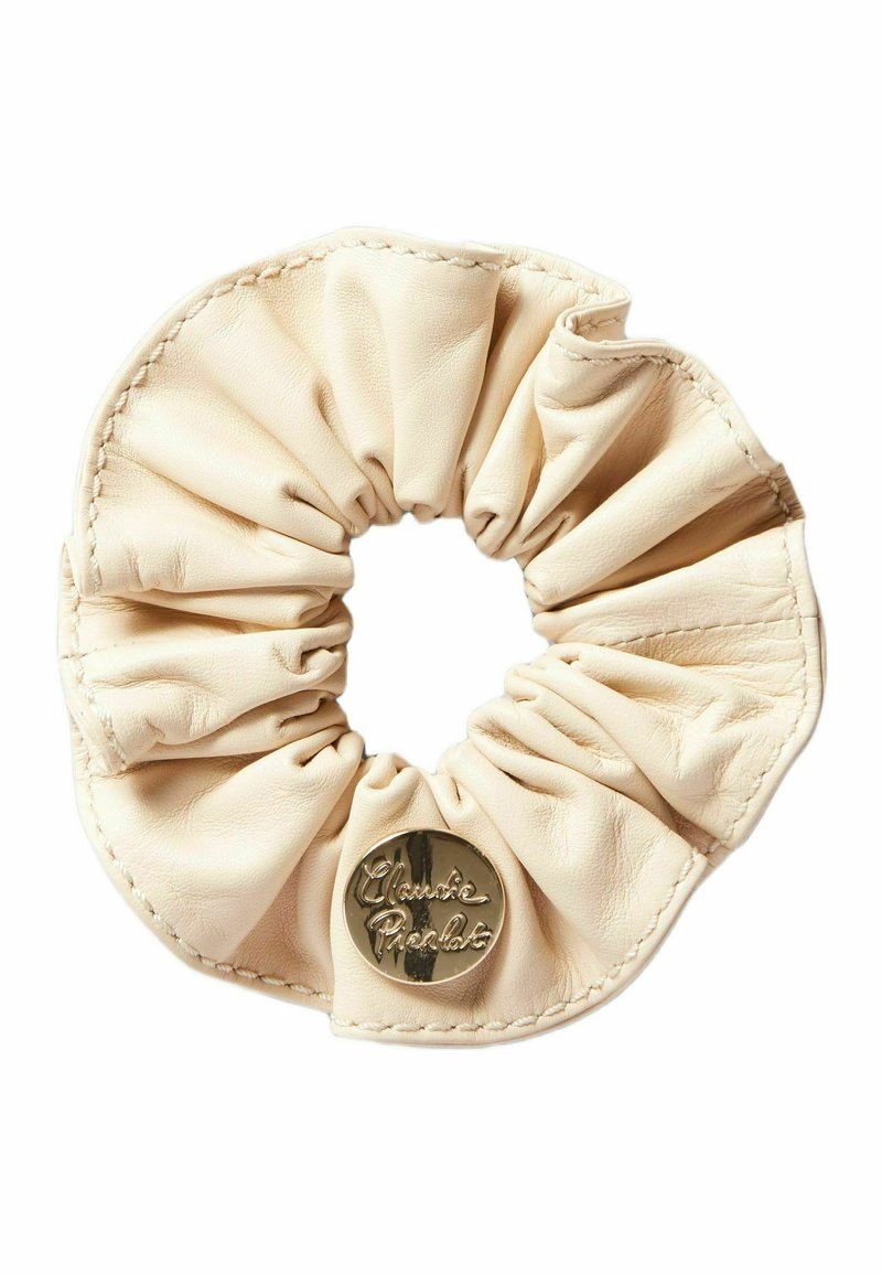 Scrunchie in pelle color crema, caratterizzata da una texture arricciata e un accento lucido con logo dorato. Morbido e liscio con dettagli di cucitura visibili.