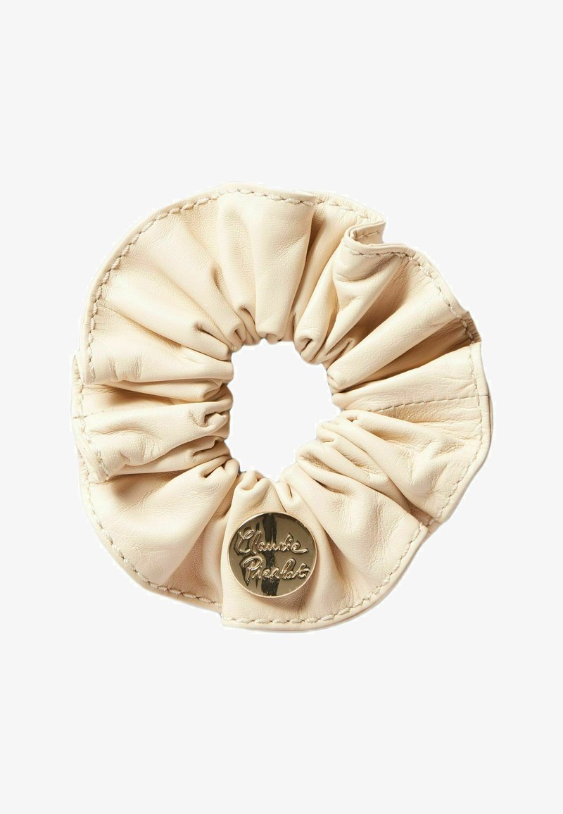 Scrunchie in pelle color crema, caratterizzata da una texture arricciata e un accento lucido con logo dorato. Morbido e liscio con dettagli di cucitura visibili.