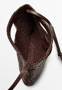 Borsa a tracolla in pelle marrone intrecciata con un interno liscio e una tracolla sottile. Design senza chiusura, con un motivo testurizzato in tutto il suo corpo.