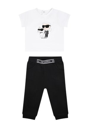 T-shirt bianca con un design a cartone animato di due personaggi con occhiali da sole, abbinata a pantaloni della tuta neri con tasche e vita elastica.