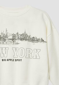 Witte sweatshirt met een zwarte lijntekening van de skyline van New York City en de tekst "NEW YORK BIG APPLE SPIRIT" in dikke letters.