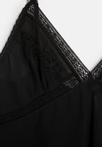 Sort cami med blondesTrim og broderede detaljer, med en glat tekstur og v-hals design. Accenter inkluderer perledekorationer.