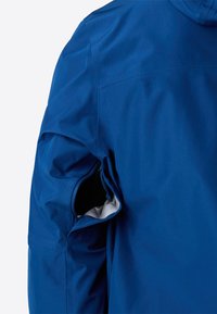 Rukáv modré bundy s otevřeným zipem pro ventilaci, který odhaluje světle šedou podšívku.