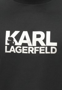 Camiseta negra de algodón con un texto blanco audaz que dice "KARL LAGERFELD" y un acento de silueta. Tejido liso y texturizado con mangas cortas.
