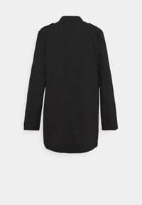 Svart kappa med långa ärmar, tillverkad av ett slätt tyg. Har en spetsig krage, bakstycke och en mittlång, rak skärning. Ingen synlig hårdvara.