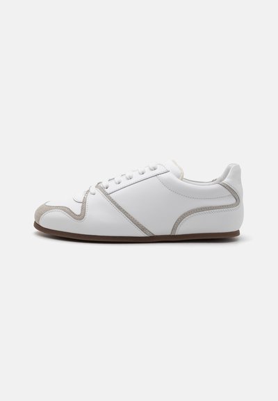 Baskets blanches avec une tige en cuir lisse, des accents en suede gris et un design de laçage simple. Semelle en caoutchouc brun antidérapante ; style minimaliste.