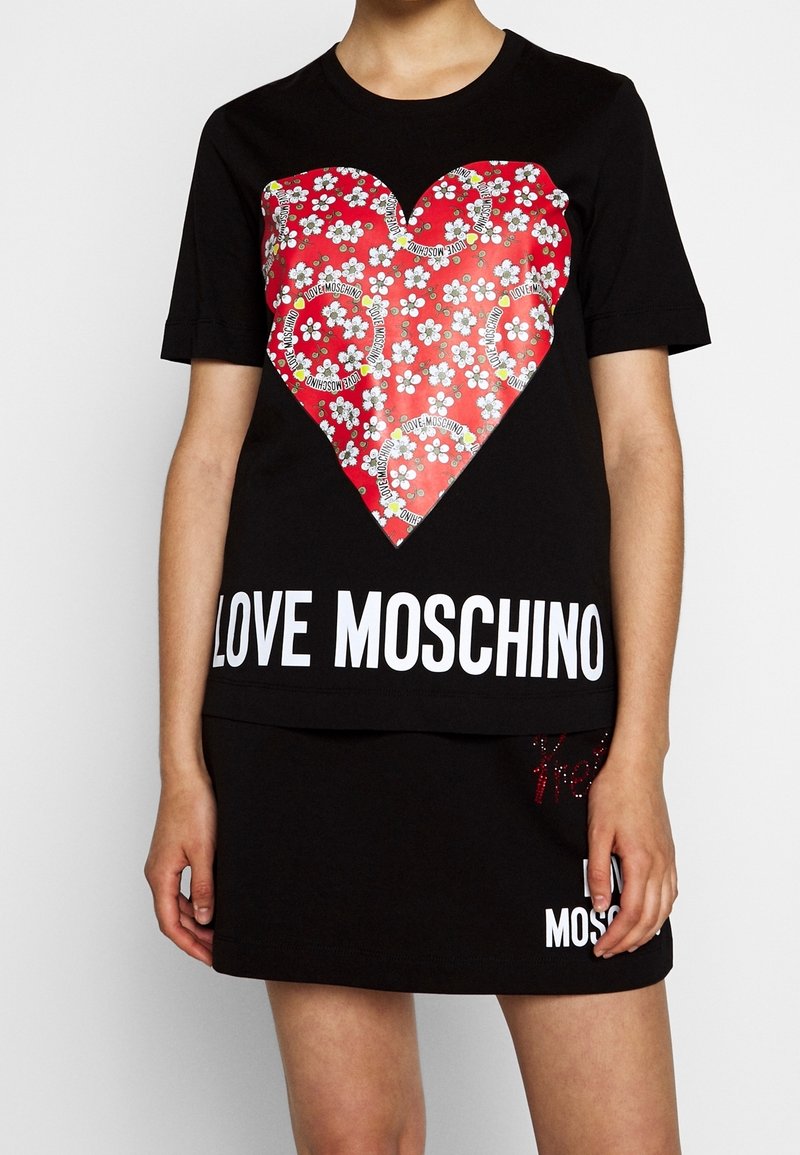 Black t-shirt featuring a large red heart graphic with floral patterns and text "LOVE MOSCHINO" in white at the base. Short sleeves.