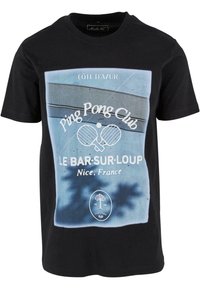 Juodas medvilnės marškinėliai su mėlynu grafikos spaudiniu, kuriame yra užrašas "Ping Pong Club", raketės ir vietos pavadinimas: "Le Bar-sur-Loup, Nica, Prancūzija."