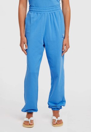 Blå joggingbukser med elastisk talje og manchetter. Blødt, tekstureret stof med en lille logo på venstre lår. Bæres med sandaler.