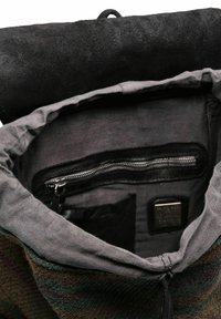 Borsa in tessuto multicolore con un morbido interno grigio. Presenta una tasca con zip, una tasca interna a scomparsa e un flap testurizzato di colore nero.