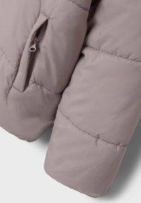 Giacca imbottita grigia chiara con un'esterno liscio, caratterizzata da sezioni cucite e una tasca con zip sul maniche per un sicuro stoccaggio.