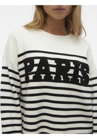 Pull rayé blanc et noir avec un logo "PARIS" texturé en noir sur la poitrine. Confectionné en fil doux, avec une coupe décontractée.
