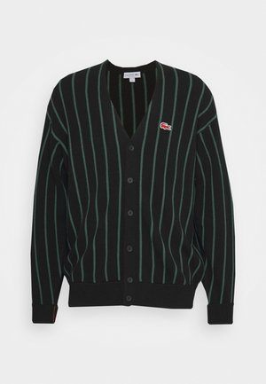Cardigan noir avec des rayures verticales vertes, fermeture à boutons sur le devant, col en V, poignets et ourlet côtelés, et un petit logo rouge sur le côté gauche de la poitrine.