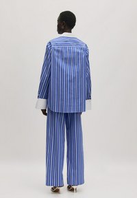 Blau-weiß gestreiftes Hemd- und Hosen-Set. Mit einem kontrastierenden weißen Kragen, langen Ärmeln und weitem Bein Design. Glatte Stoffstruktur.