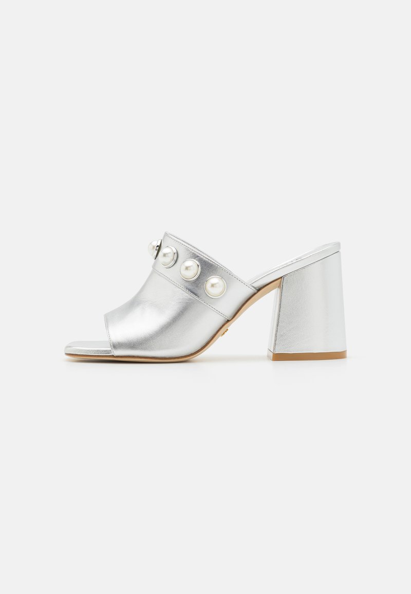Mules métalliques argentées à talons avec une pointe ouverte, ornées de trois grands accents en perles rondes et d'un talon bloc épais. Texture lisse sur toute la surface.