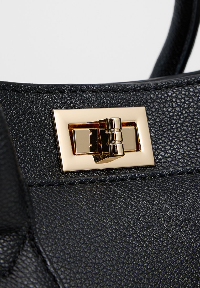 Bolso de cuero negro con un cierre en tono dorado, de forma rectangular y acabado texturizado, que destaca por los detalles de su herrajes.