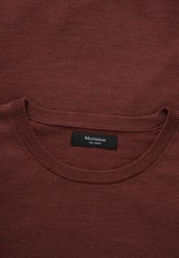 Vyno raudonos spalvos džemperis su apvalia iškirpte, pagamintas iš 100% merino vilnos. Turi gulate įsiuvą ir lygų, tekstūruotą audinį su etikete vidinėje pusėje.