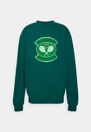 Ciemnozielona bluza z emblematem "NY Concept Tennis Club" przedstawiającym dwie skrzyżowane rakiety tenisowe i małą czerwoną piłkę tenisową.