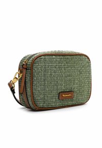 Bolsa de tela verde tejida con forma rectangular, detalles en cuero marrón, herrajes dorados y cierre de cremallera.
