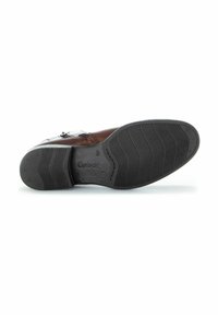 Chaussure en cuir marron avec une semelle en caoutchouc noir texturé et des accents décoratifs sur les côtés. Présente une forme arrondie avec un petit talon.